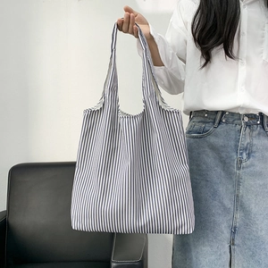 Detailed shot of large blue and white striped canvas tote bag held by a model
