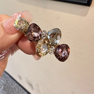 Détail de la pince à cheveux en cristal avec strass en forme de goutte violets et champagne