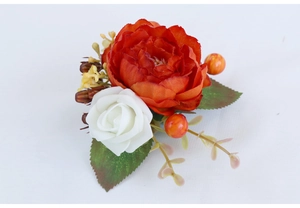 Detail of a handmade orange silk rose boutonniere with white foam rose and green leaves
