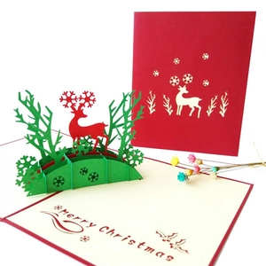 3D pop-up Christmas card featuring a red reindeer and green trees in a snowy forest scene
