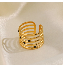 Detail view of gold five-layer open ring with black enamel dots on beige silk