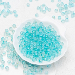 Macro shot of 6mm blue frosted glass beads with gold sparkles in a white shell bowl