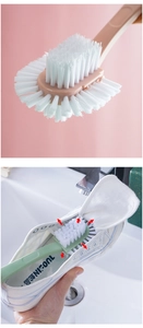 Detail showing high-density white bristles and green long-handle shoe brush in cleaning use