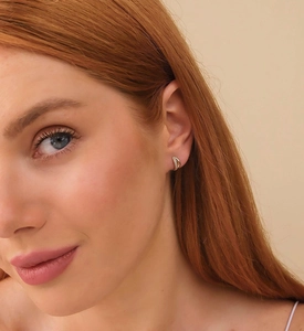 Close-up of elegant small gold hoop earrings with micro-inlaid zircons on model ear