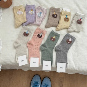 Flat lay of colorful cotton socks with cute cartoon bear embroidery and dotted yarn