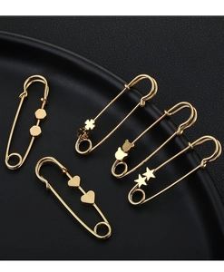 Detailed view of five gold metal safety pins with diverse charms on a black surface