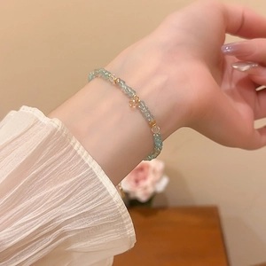 Close-up of light blue crystal beaded bracelet with gold star charm on female wrist