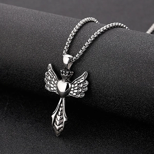 Macro shot of silver angel wing heart pendant with textured point on black background