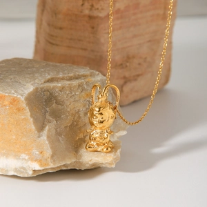 Detailed close-up of golden Wukong pendant on a textured rock showing fine relief work