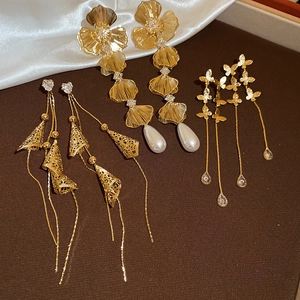 Detail of 18K gold plated earrings featuring flowers, butterflies and faux pearls
