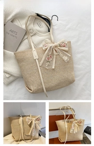 Close-up of beige straw tote bag with delicate pink floral embroidery and lace bow detail