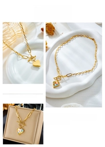 Close-up of golden OT buckle chain necklace featuring a colorful crystal heart pendant