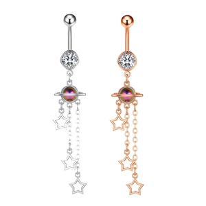 Detail of silver and rose gold belly rings with planet design and star zircon tassels