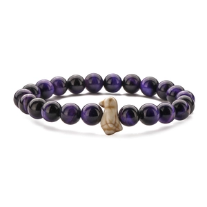Macro detail of elastic beaded bracelet with violet cat-eye stones and beige bird charm
