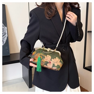 Detail of dark green floral handbag with pearl chain and tassel on black suit