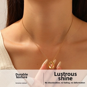 Detailed close-up of a polished gold oval pendant on a fine chain necklace worn by a model
