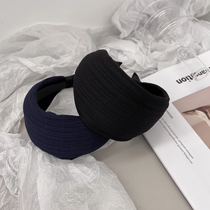 Detail showing black and navy blue ribbed headbands on a textured fabric background