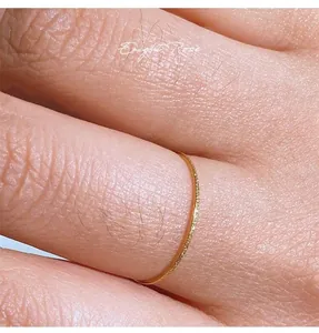 Close-up of 18K gold ultra-thin frosted band ring with shimmering sand finish