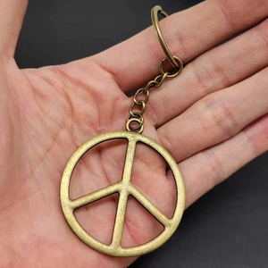 Vintage bronze peace symbol keychain with rustic metal finish held in palm