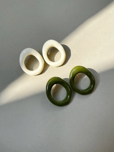 Close-up of geometric oval resin earrings in cream and dark olive green colors
