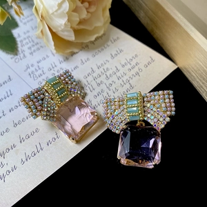 Macro detail of pink square crystal earrings with pearl butterfly bow in gold finish