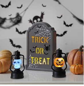 Close-up of lighted LED pumpkin lantern and trick or treat tombstone for Halloween decor