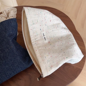 Close-up of white canvas makeup bag with blue denim pouch on a wooden table