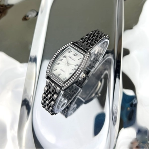 Detail of Grealy tonneau watch with emerald dial, crystal bezel, and black strap
