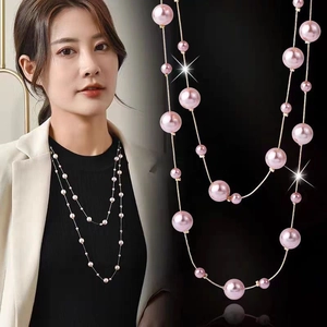 Detail of pink pearl long necklace featuring gold chain layers for elegant styling