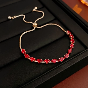 Close-up of golden adjustable bracelet with red marquise-cut stones on a black display