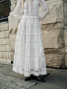 Detailed view of intricate lace crochet patterns and hollow out design on a white maxi dress