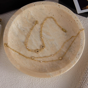 Dettaglio di un bracciale dorato in acciaio inossidabile con ciondoli a cuore e diamanti