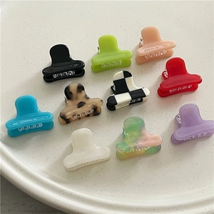 Flat lay of colorful mini acetate hair claws in various vibrant patterns and solid colors