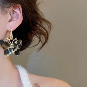 Detailed view of vintage leopard print butterfly earrings with golden metal frames on model