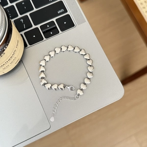 Minimalist silver heart link bracelet displayed on a sleek laptop with a scent bottle