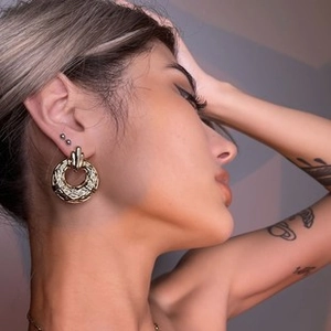 Close-up of vintage gold hoop earrings with textured diamond quilted pattern on model