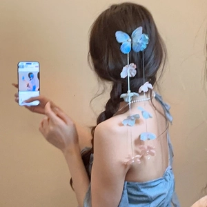Detail of blue fabric butterfly hair clip with floral tassels worn on long hair