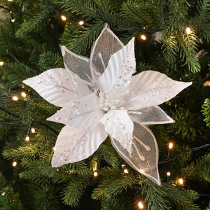 White 28cm artificial poinsettia with sequins on a Christmas tree with warm LED lights