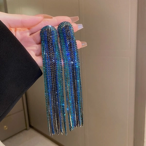 Close-up of long tassel earrings with sparkling blue and black rhinestones and starburst effect