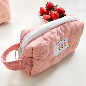 Dettaglio dell'astuccio trapuntato rosa con cerniera bianca ed etichetta in tessuto floreale