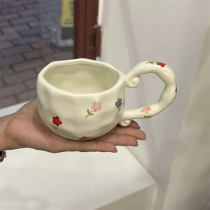 Detail of hand-painted floral ceramic coffee mug with irregular wavy texture and spiral handle