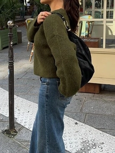 Street style shot of olive green knitted sweater with long sleeves for women in 2025 fashion