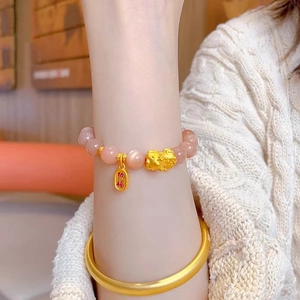 Detailed shot of sunstone beaded bracelet with golden Pixiu and Na Fu charm on wrist