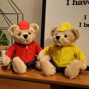 Cute teddy bears in red and yellow jackets with matching caps on a wooden table