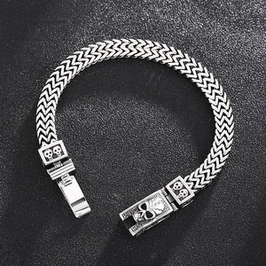 Detail of masculine skull head clasp on silver double-row woven chain bracelet