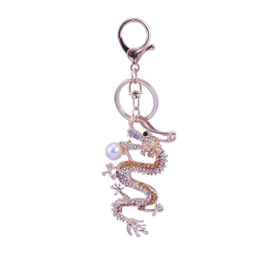 Golden dragon keychain with sparkling rhinestones and white pearl accent on white background