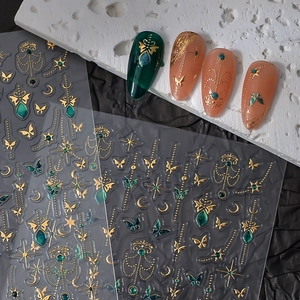 Macro detail of gold butterfly and star nail stickers with luxury teal metallic finish
