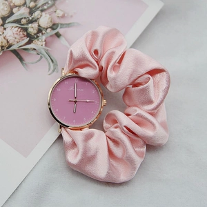 Detailed shot of pink ribbon scrunchie strap watch with rose gold dial and floral card