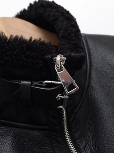 Détail d'une veste en cuir noir avec col en mouton retourné et fermeture éclair en métal