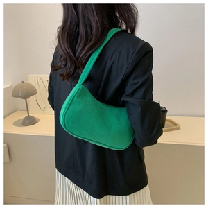 Green corduroy underarm bag shown on model with black suit and white skirt